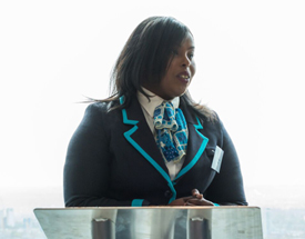 A graduate of Barclays Bank's apprenticeship program in the UK speaks at a graduation ceremony for a cohort of apprentices.