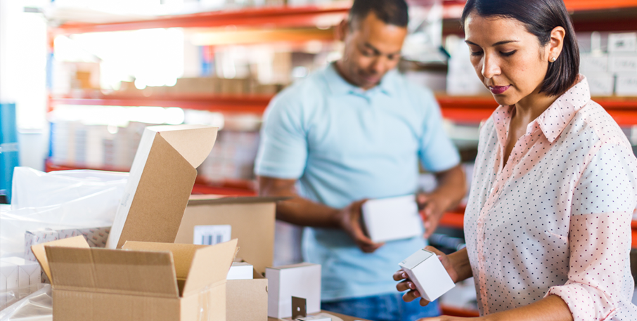 A man and woman pack boxes at their small business's warehouse.