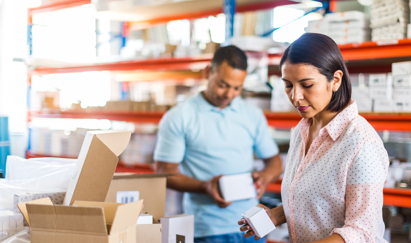 A man and woman pack boxes at their small business's warehouse.