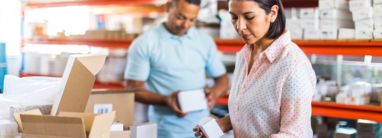 A man and woman pack boxes at their small business's warehouse.
