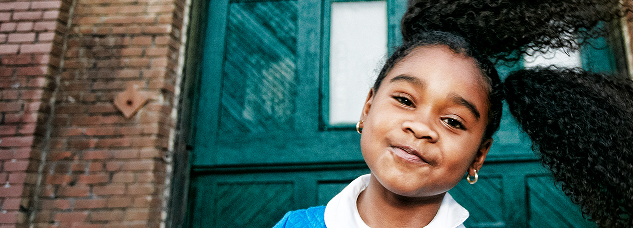 A little girl swings her curly pigtails to the side.