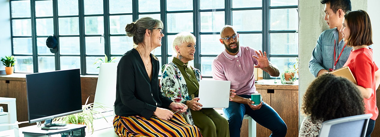 Group of coworkers in an office, talking with one another.