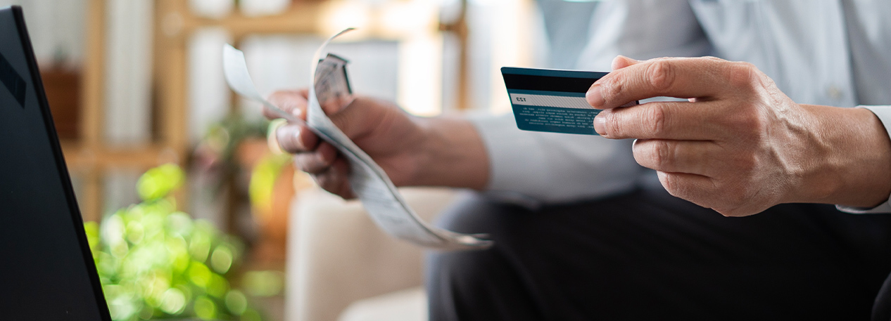 Someone holding a credit card and a bill