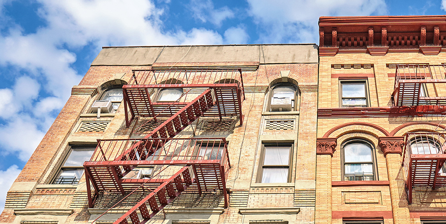 Top two floors of an urban apartment building with metal fire escapes