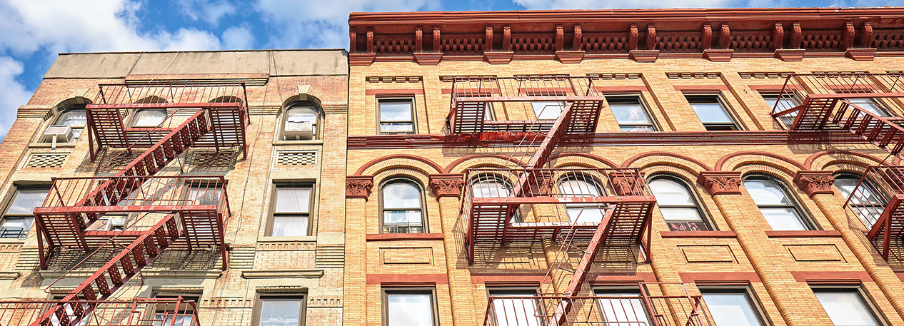 Top two floors of an urban apartment building with metal fire escapes