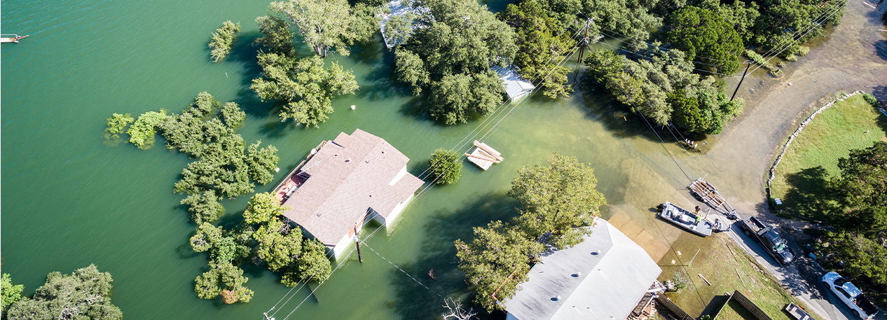 Overhead view of a rural area with a number of flooded buildings next to a body of water.