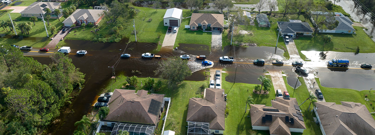 Aerial photo of a line of cars driving down a flooded suburban street.