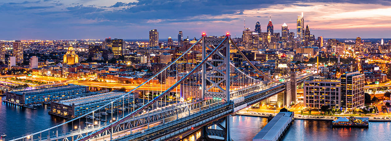 A twilight view of the Philadelphia skyline with the Ben Franklin Bridge in the foreground.