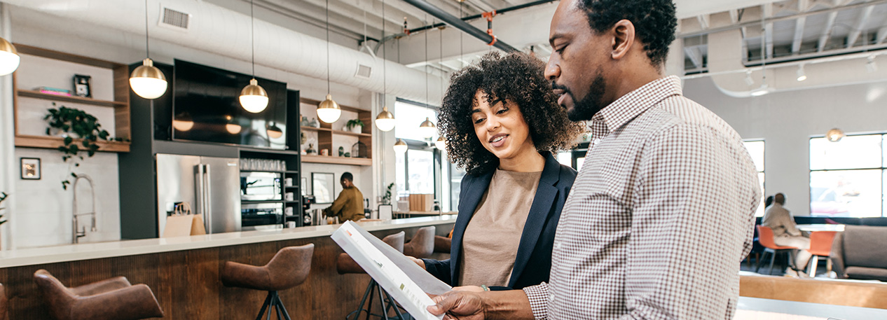 Man and woman looking at a paper while standing in front of a coffee bar.