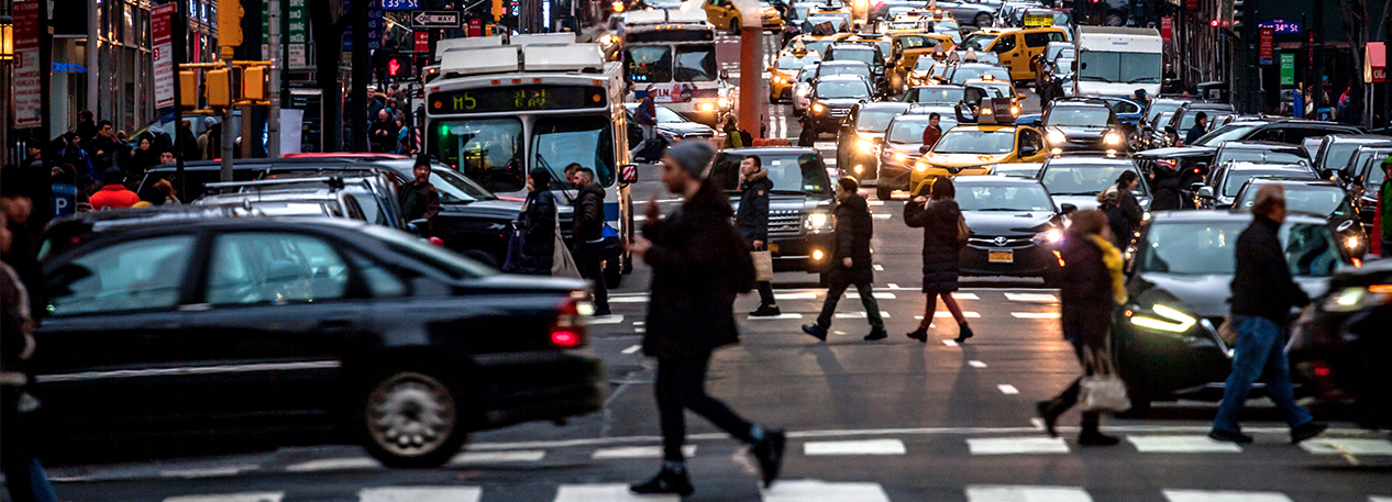 Cars, busses, and people on a busy city street.