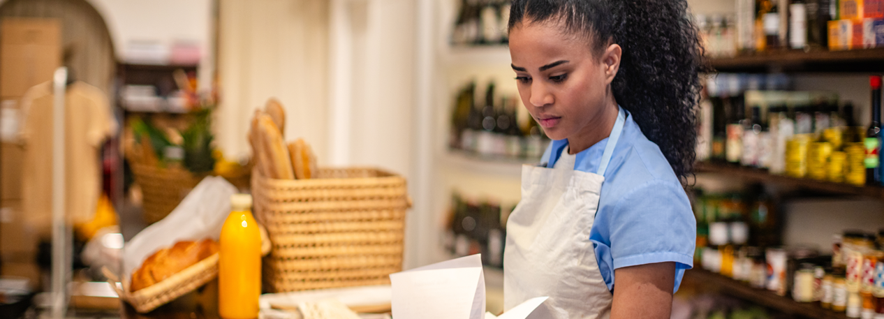 Individual is attending a store counter while looking through papers