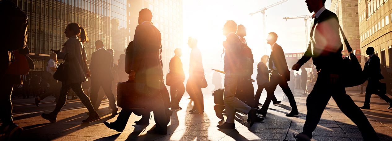 Silhouettes of a crowd of people crossing a city street.