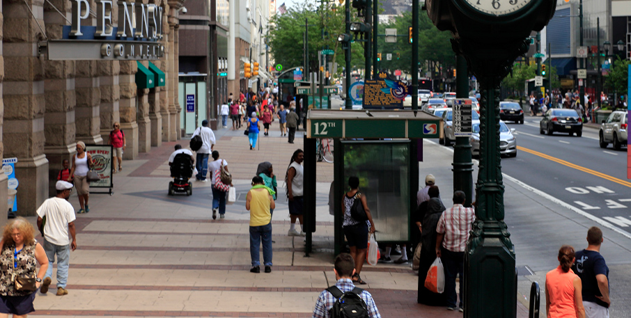 People walking on the sidewalk alongside a city street.