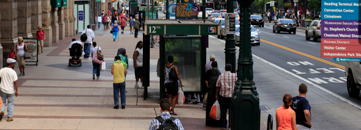 People walking on the sidewalk alongside a city street.