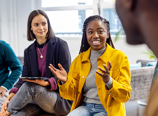 Two colleagues listen while a third explains an idea and gestures with her hands.