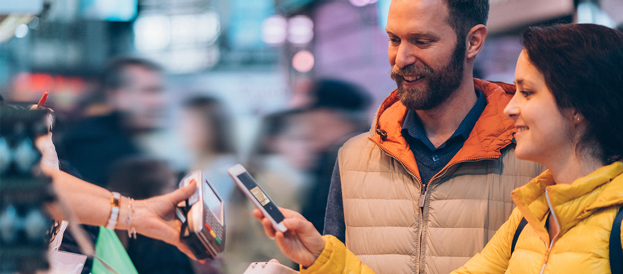 Woman paying with her cell phone while a man watches