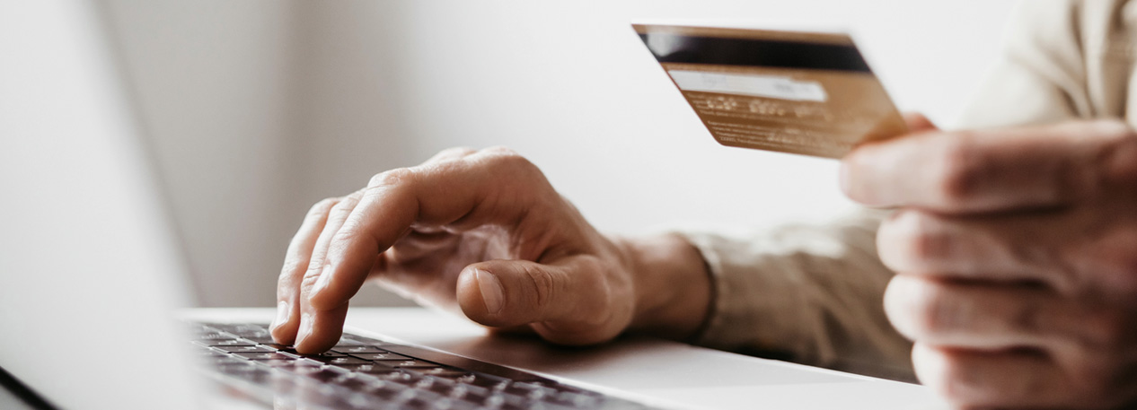 Hand holding credit card while using a laptop