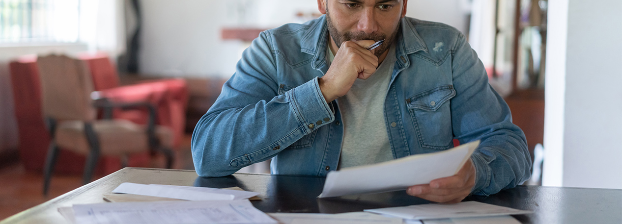 A man reviews bills with a look of concern on his face.