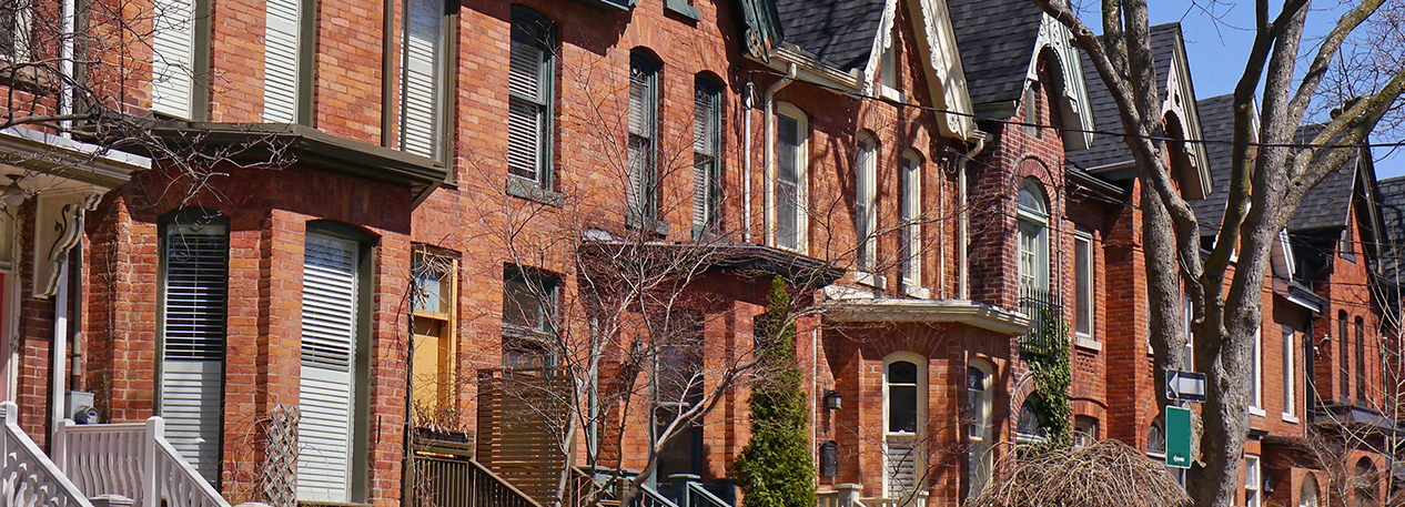 The sun shines on a city block of brick row homes.