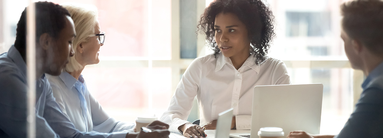 Woman with laptop computer speaking with coworkers