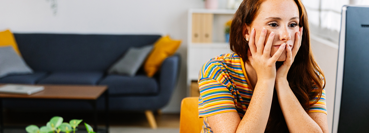 A woman staring at a computer with her head in her hands