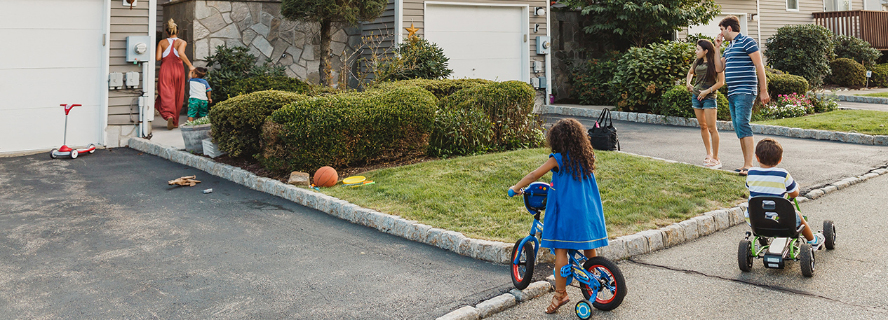 Children playing in the driveway and on the sidewalk outside the family's home