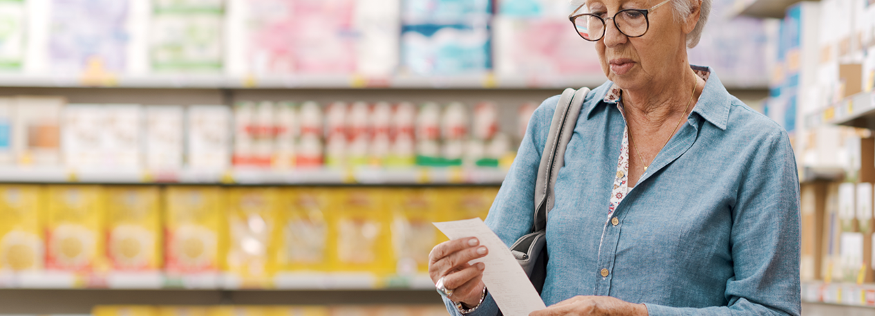 Elderly woman reviews receipt in the grocery store.
