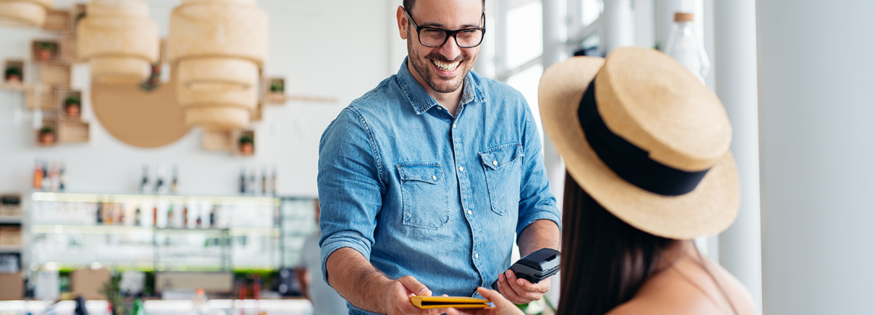 Waiter holding a credit card reader and handing the bill to a woman in a hat