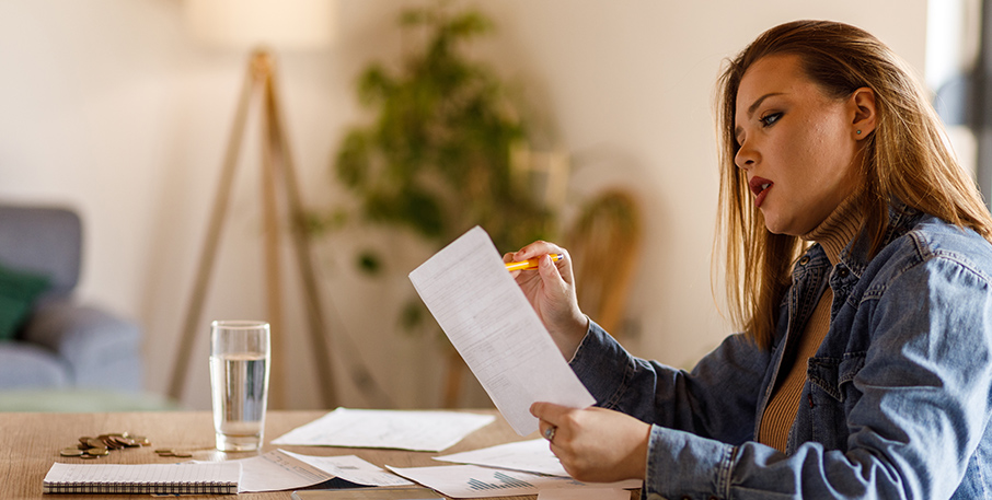 A woman reviews paperwork at the kitchen table.