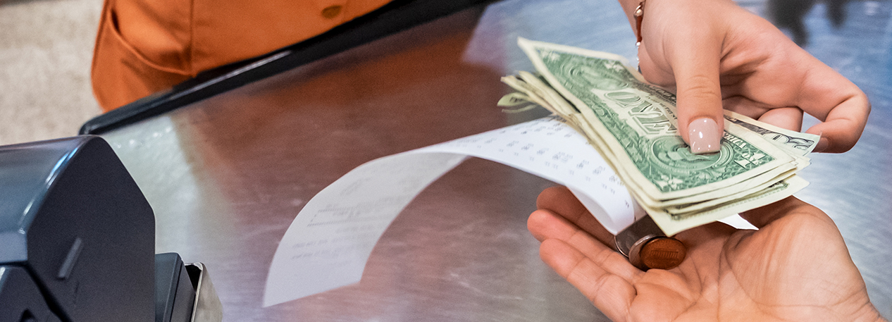 Close up of customer receiving change and a receipt from a cashier