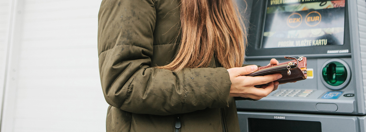 Woman standing in front of an ATM and opening her wallet