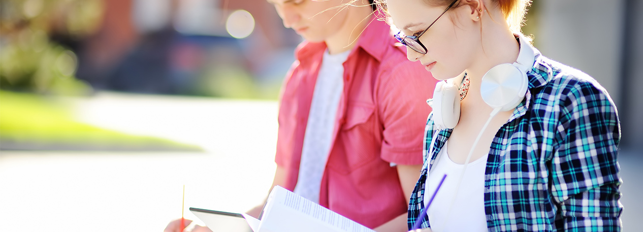 Two college-age students outside, studying