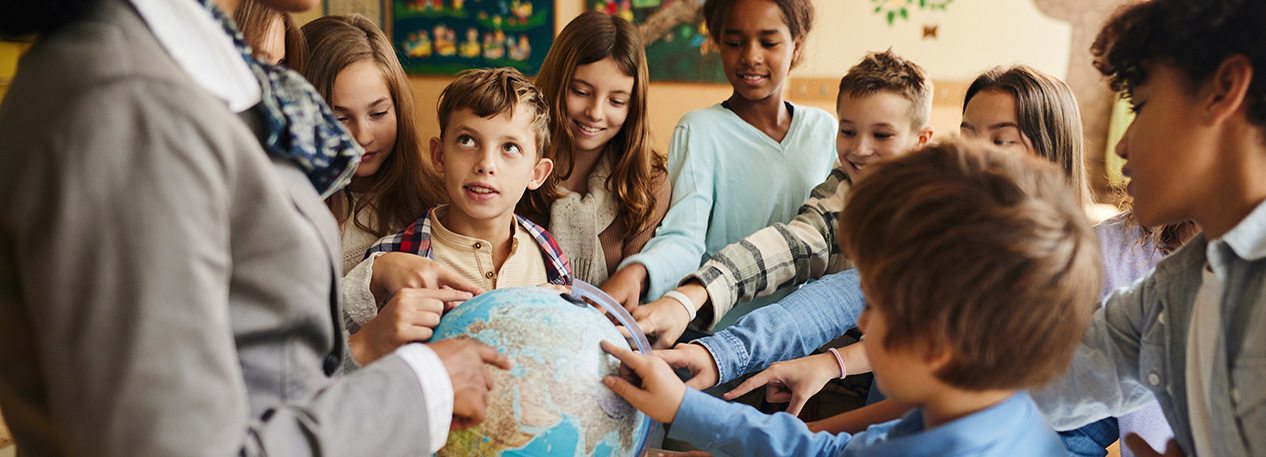 Students pointing to places on a globe