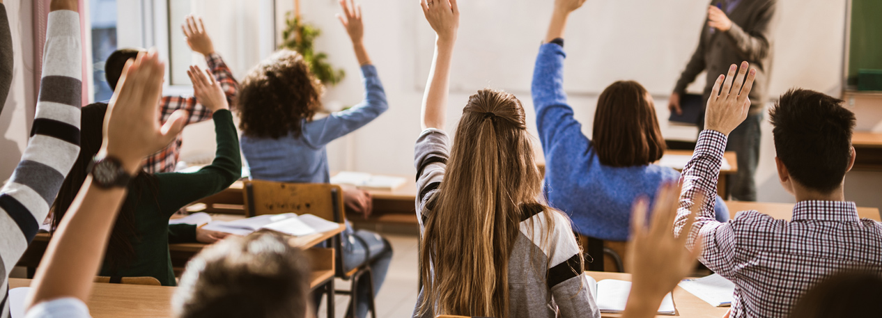 A classroom of high school students with their hands raised
