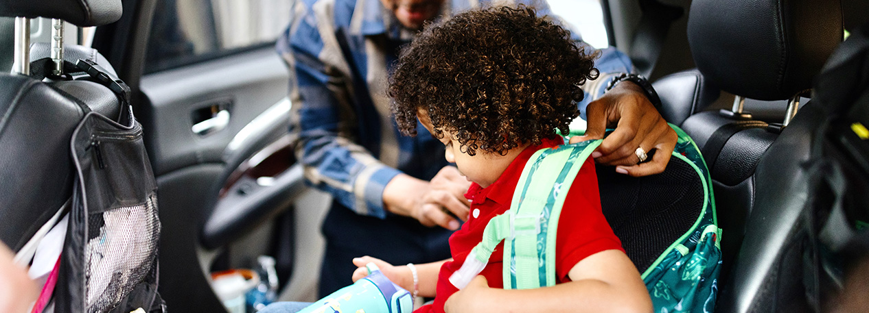 A man buckles a small child into a carseat.