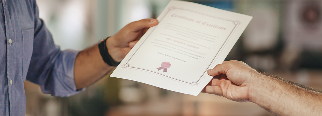 Close up of someone handing another person a certificate.