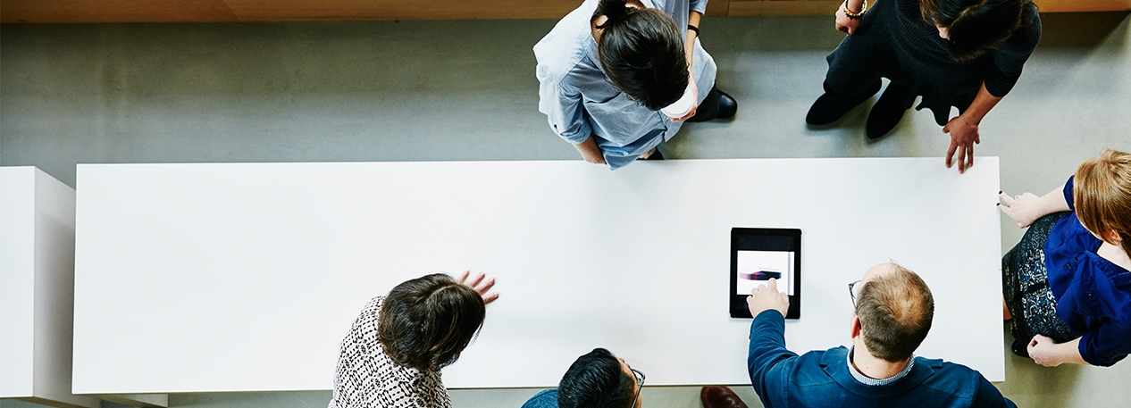 Co-workers collaborating at a meeting table, viewed from above.