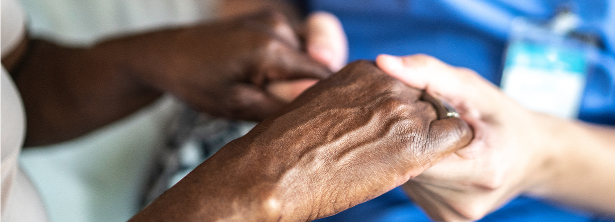 Close-up of home caregiver and senior woman holding hands.