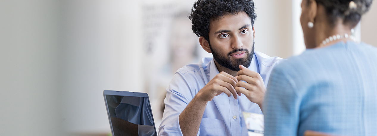 A woman and man sit across from one another at a desk and review a financial document.