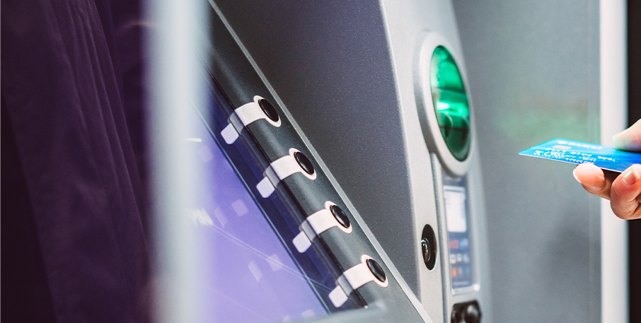 A woman prepares to slide her debit card into an ATM.