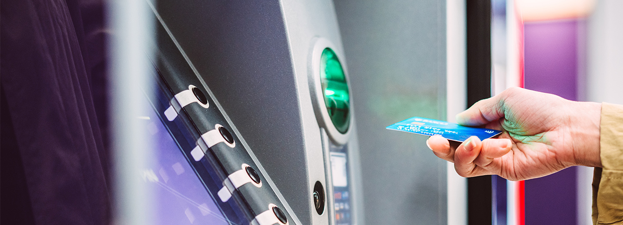 A woman prepares to slide her debit card into an ATM.