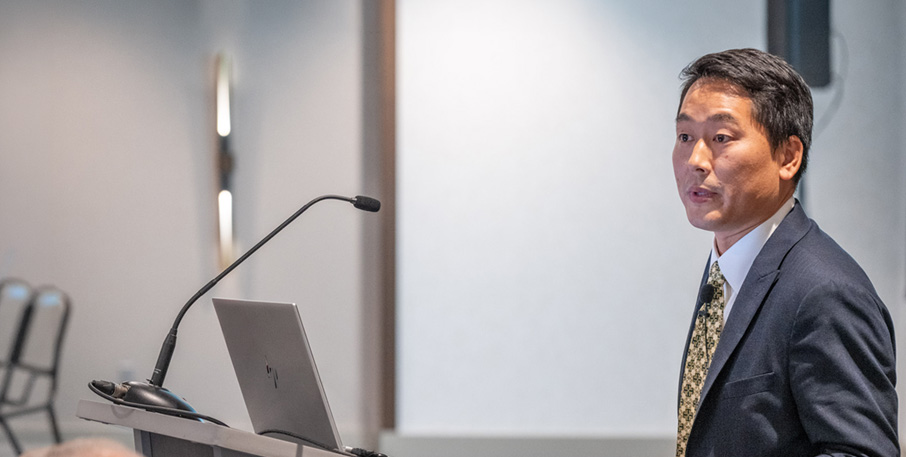 Outreach Economist and Advisor Ryotaro Tashiro speaks from a podium.