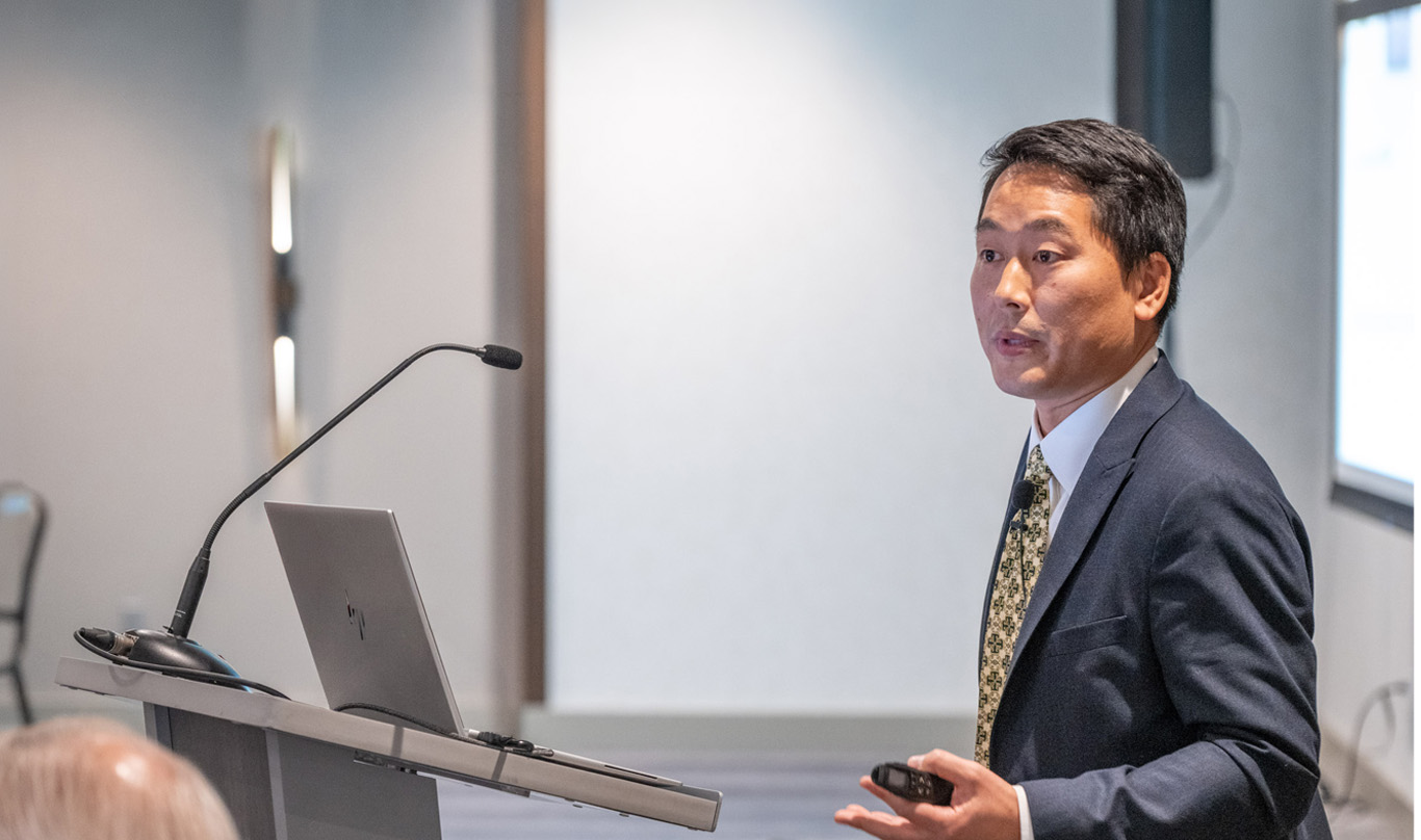 Outreach Economist and Advisor Ryotaro Tashiro speaks from a podium.