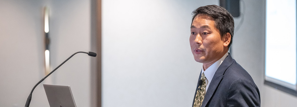 Outreach Economist and Advisor Ryotaro Tashiro speaks from a podium.