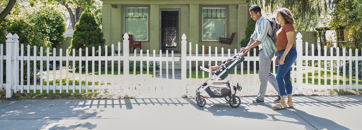 People walking baby in stroller on sidewalk