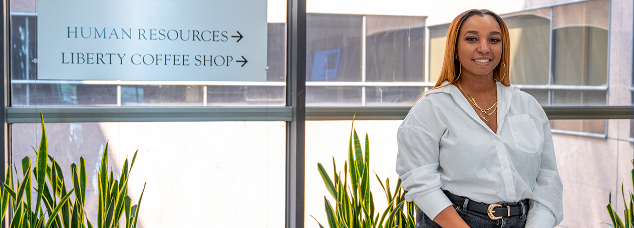 Philadelphia Fed employee Cydnee Bryant standing in front of a window in the Bank offices.
