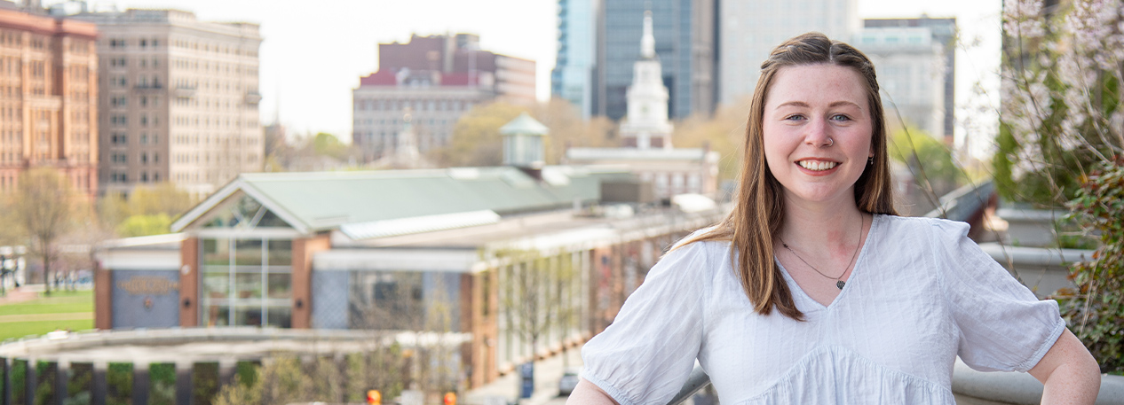 Maggie Young standing on a balcony with Independence Hall in the background.