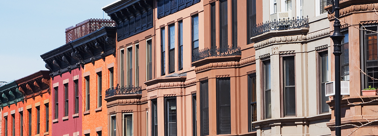 The front entrances and windows of a row of townhouses and brownstones