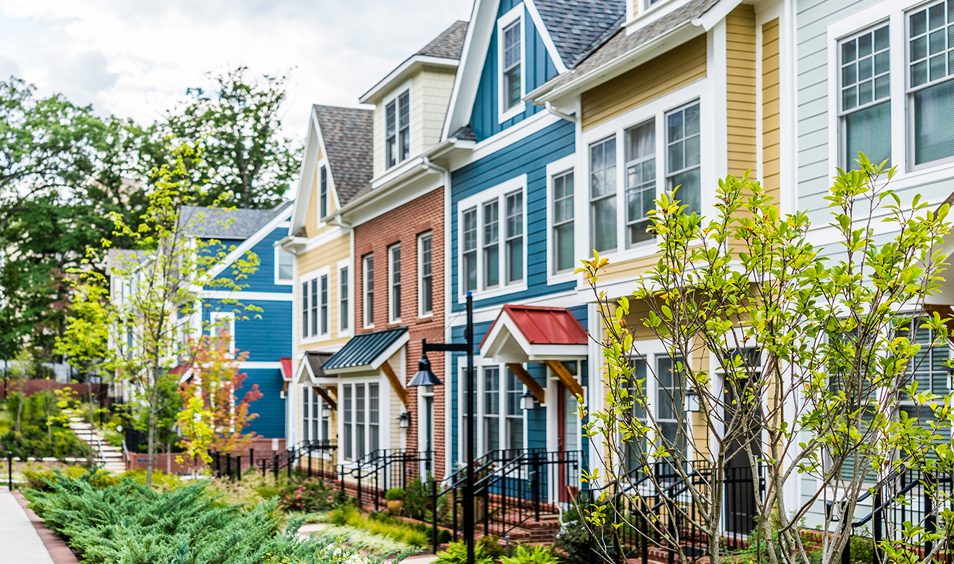 A colorful townhouse development with a long garden of bushes and small trees