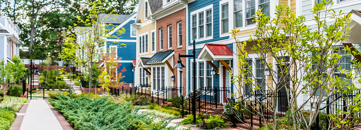 A colorful townhouse development with a long garden of bushes and small trees